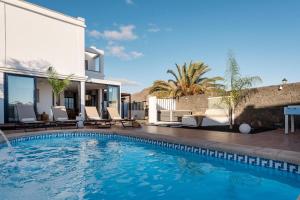 a swimming pool in front of a house at Villa Zendaya in Yaiza
