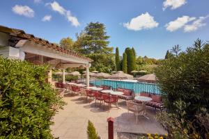 a patio with tables and chairs next to a pool at La Bastide de Mougins, a Tribute Portfolio Hotel in Mougins