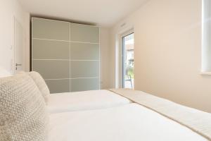 a white bedroom with a bed and a window at Chiemsee Apartment 17 in Übersee