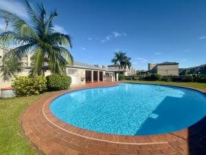 a large blue swimming pool in front of a house at KADESE Holiday North Beach Durban in Durban