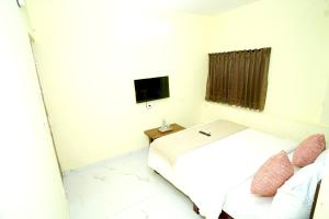 a white room with a bed and a television at Sri Sai comforts - Bannerghatta Main Road in Bangalore