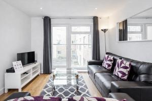 a living room with a black leather couch and a tv at Roomspace Serviced Apartments - Abbot's Yard in Guildford