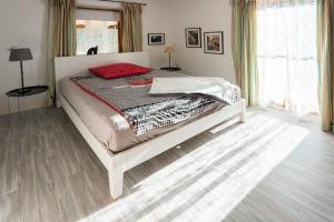 a bedroom with a white bed with a red pillow at Ferienwohnung Lois ***** in Eggstätt