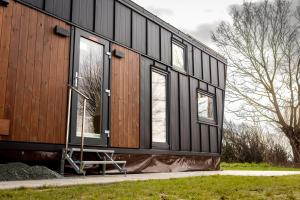 ein schwarzes Haus mit Fenstern an der Seite in der Unterkunft Tiny House - Rolling Tiny - Wanderfalke in Groß Kordshagen