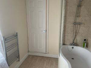 a bathroom with a tub and a shower and a door at Babo Bolton room en suite in Farnworth