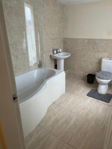 a bathroom with a tub and a sink and a toilet at Babo Bolton room en suite in Farnworth