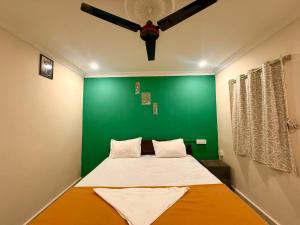 a bedroom with a green wall and a bed at Capital Stay Inn in Vijayawāda +8 photos