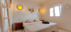 a white bedroom with two beds and a window at VelenaRubia in Vélez-Málaga