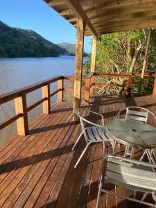 a wooden deck with a table and chairs on the water at Recanto Nativos in Garopaba