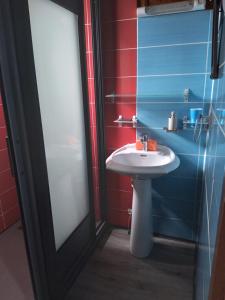 a bathroom with a white sink next to a glass door at Chalet Des Primevères in Cilaos