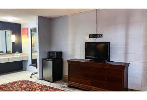 a living room with a tv on a dresser and a bathroom at Studio 6 Suites Albany, GA in Albany +25 photos