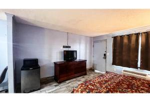 a living room with a tv and a tv stand and a television at Studio 6 Suites Albany, GA in Albany