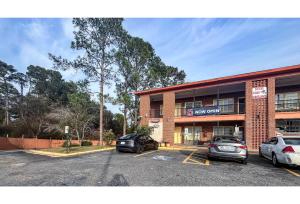 a building with two cars parked in a parking lot at Studio 6 Suites Albany, GA in Albany
