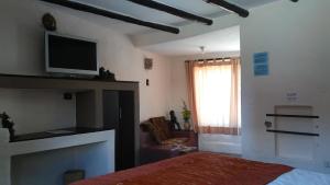 a bedroom with a bed and a tv on the wall at Pozo del Cielo in Chivay