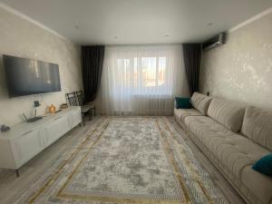 a living room with a couch and a flat screen tv at Elegant Home Stepnoy in Karagandy