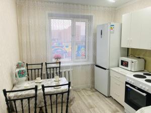 a kitchen with a table and chairs and a refrigerator at Elegant Home Stepnoy in Karagandy