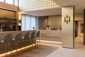a hotel lobby with a bar with stools at Hôtel des Innovations - Hôtel & Appartements - Votre séjour entre Fribourg, ville médiévale et La Gruyère et ses Bains in Marly-le-Grand