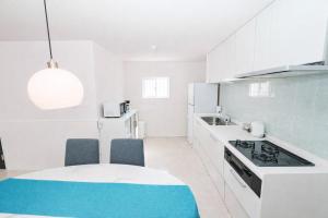 a kitchen with white cabinets and a table and chairs at Sunstone Residence 2F - Free Rental Car & Airport Pickup - 10 Min to American Village in Ginowan