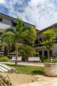 a park with benches and palm trees in front of a building at Alimar Hotel in Natal