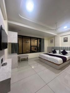 a bedroom with a large bed and a large window at Hotel Sun Icon in Vadodara