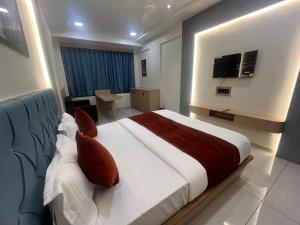 a bedroom with a large bed with a tv on the wall at Hotel Sun Icon in Vadodara