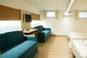 a living room with two blue couches and a tv at Le Gemelle Boutique Hotel in Torre Suda