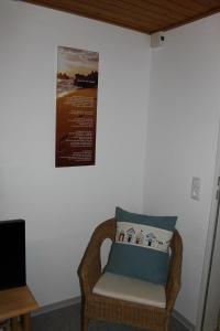 a wicker chair in a room with a picture on the wall at Ferienwohnung Küssner in Kiel