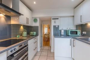 a kitchen with white cabinets and a microwave at Spacious Seafront Apartment, Garden Free Parking in Littlehampton