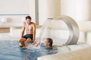 a man and two girls playing in a swimming pool at Iberostar Waves Royal Andalus in Chiclana de la Frontera