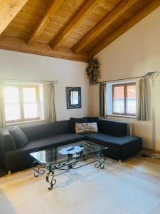 a living room with a black couch and a glass table at City Apartment in Oberammergau