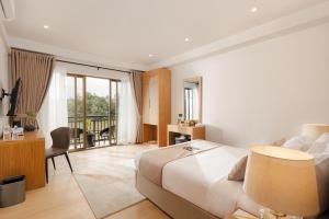 a bedroom with a bed and a desk and a balcony at Royal Avenue Kandy in Kandy