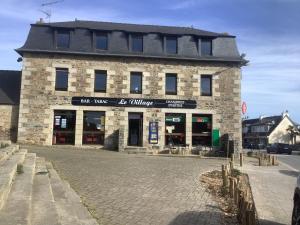 a large stone building with a store on a street at Le village Gr34 louannec in Louannec