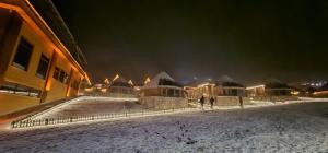 a group of buildings covered in snow at night at Snow Dreams Bungalow Hotel in Türkmenoğlu
