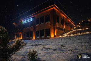 a building with a sign on it in the snow at Snow Dreams Bungalow Hotel in Türkmenoğlu