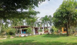 a house with trees in front of a yard at Chan Klong No8 Homestay - บ้านชานคลองหมายเลข8 in Sathani Wat Sing