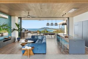 a living room with a blue couch and a kitchen at Infinity Pool Villa , 4 Suites & Private Casita in Tamarindo