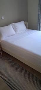 a bed with white sheets and pillows in a room at 3C Palm Ridge Vipingo in Kilifi