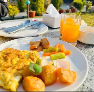 a plate of food with eggs and vegetables and a glass of orange juice at Paradise Boutique Hotel in Pokhara