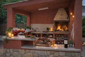 an outdoor kitchen with a fireplace and a table with wine glasses at Villa Sitges La Calma 10 minutes drive Sitges 2 minutes walk Garraf Park AC in Sant Pere de Ribes