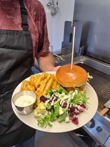 a man holding a plate with a sandwich and french fries at Camping le beauvillage Lauzerte in Lauzerte