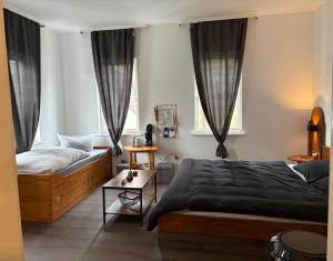 a bedroom with a bed and a couch and two windows at Junges Wohnen zwei in Weikersheim