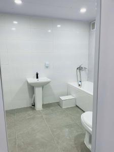 a white bathroom with a sink and a toilet at Tara Guesthouse and Tours in Ulaanbaatar