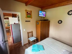 a bedroom with a bed and a tv on the wall at Cabaña Lago Puyehue in Mantilhue