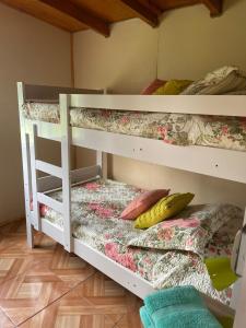 two white bunk beds in a room with a bed at Cabaña Lago Puyehue in Mantilhue