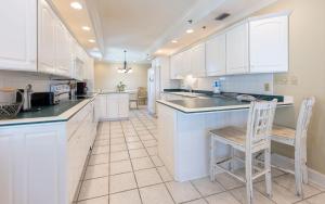 a kitchen with white cabinets and a table and chairs at Phoenix East 1401 in Orange Beach