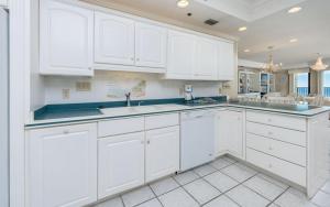 a white kitchen with white cabinets and blue counter tops at Phoenix East 1401 in Orange Beach +69 photos