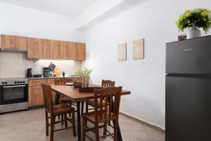 a kitchen with a wooden table with chairs and a refrigerator at Andros Apartments with Free Parking in Steniaí