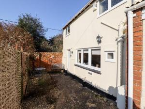 a white house next to a brick fence at Vine Cottage in Halstead