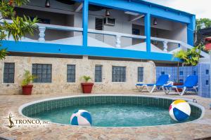 Hotel El Tronco Inc في بوكا شيكا: حمام سباحة مع كرات الشاطئ أمام المبنى