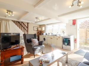 a living room with a television and a chair at Vine Cottage in Halstead